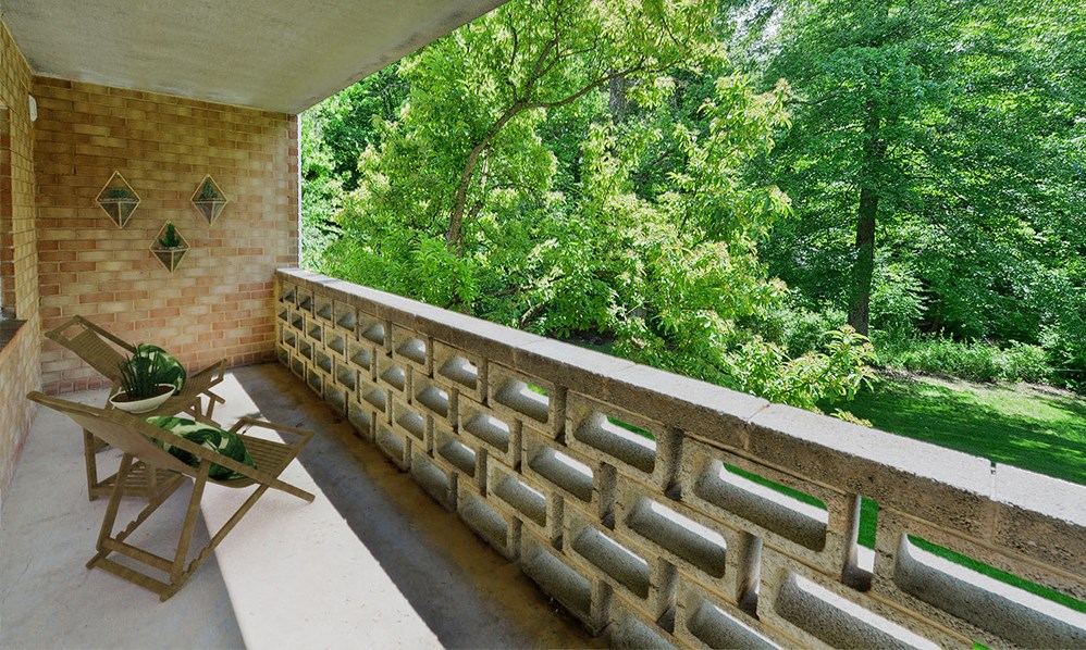 a balcony with a table and chairs and a wall with trees