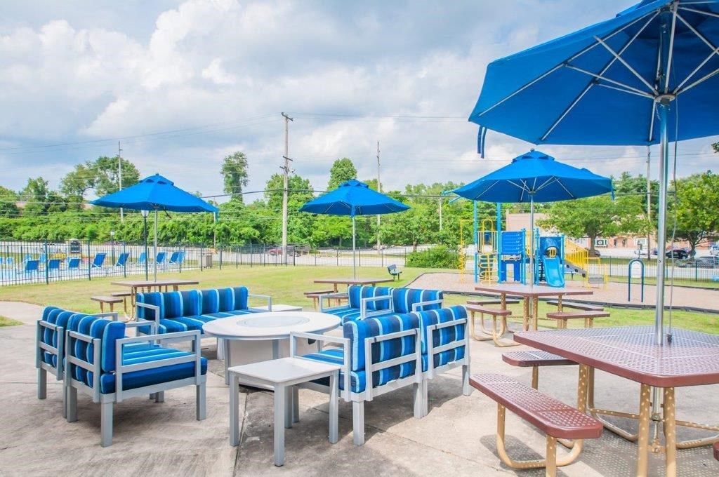 a patio with tables chairs and umbrellas at a park