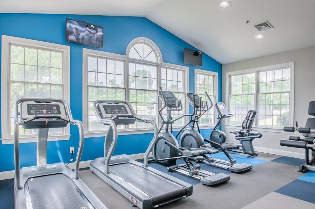 a gym with cardio equipment and windows on the wall