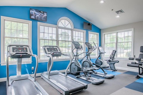 a gym with cardio equipment and windows on the wall