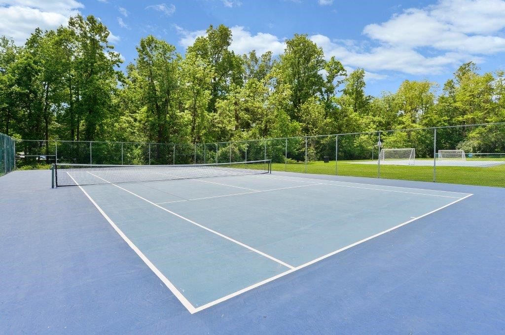 a tennis court with a fence and trees in the background