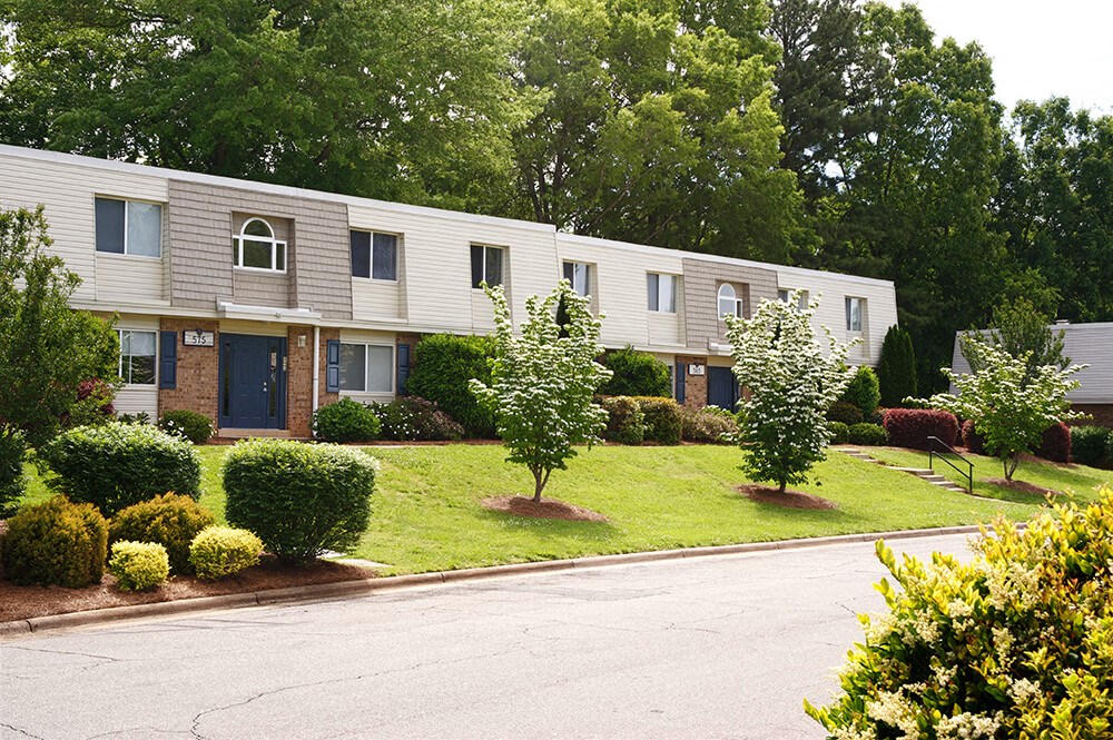 an exterior view of an apartment building with trees and bushes