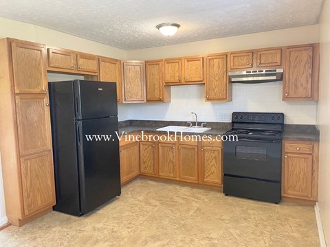 a kitchen with wooden cabinets and a black refrigerator