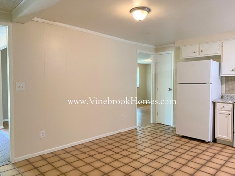 A kitchen area with a white refrigerator and a tiled floor.