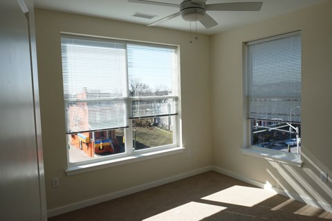 a living room with two large windows and a ceiling fan