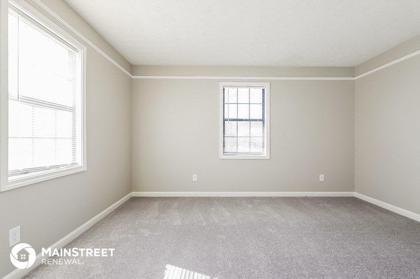 a bedroom with two windows and a carpeted floor