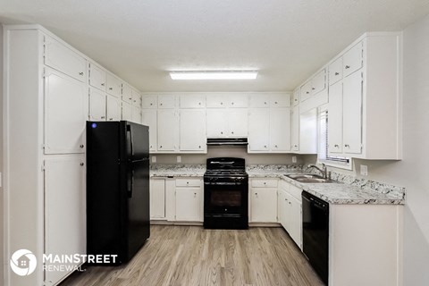 a kitchen with white cabinets and black appliances