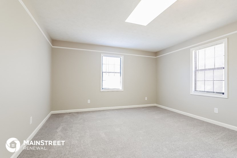 a bedroom with a carpeted floor and two windows