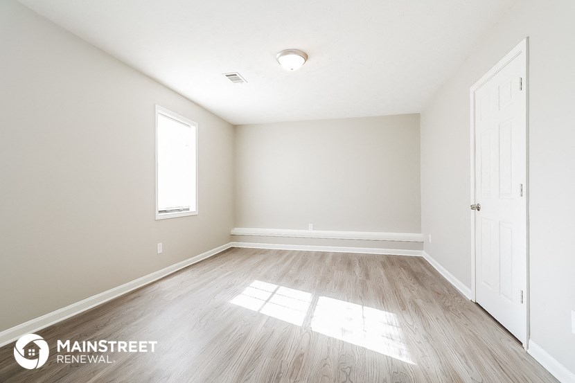 the spacious living room with wood flooring and white walls