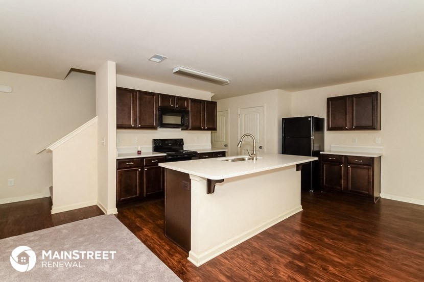 a kitchen with a white counter top and dark wood cabinets