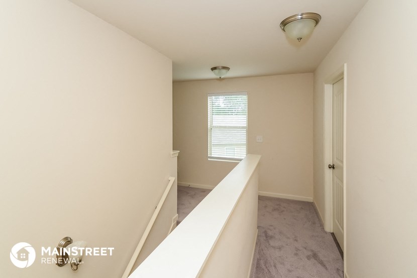 the upstairs hallway of an apartment with a staircase and a window