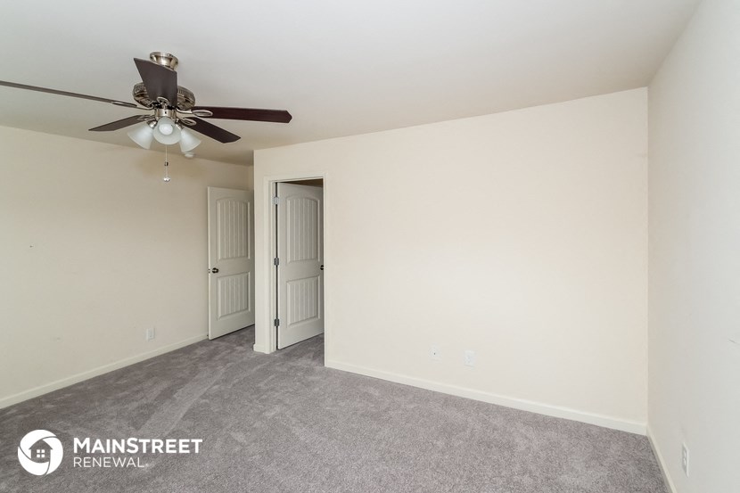 the spacious living room with ceiling fan and carpeting