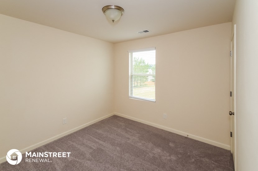 the living room of a house with carpet and a window