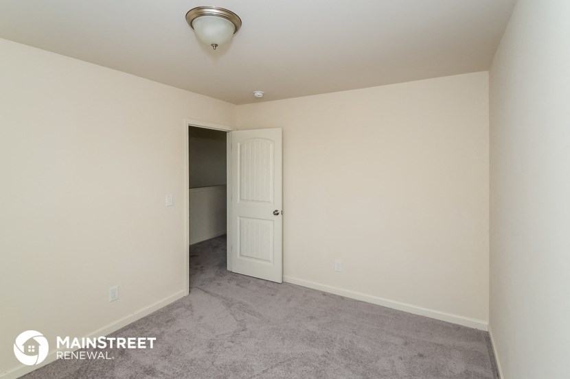 a white room with a door and a hallway to a closet
