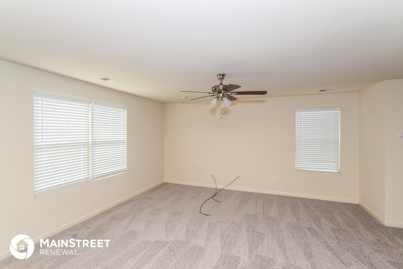 the living room of an empty house with a ceiling fan