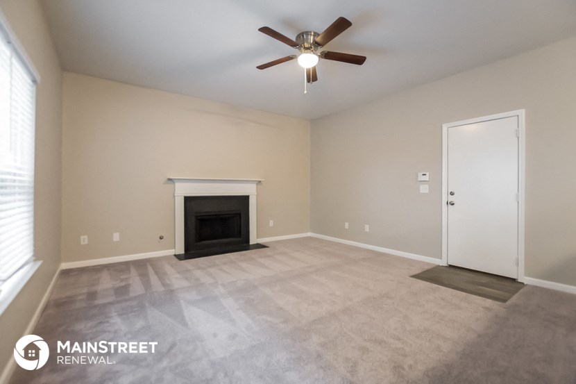 the spacious living room with fireplace and ceiling fan