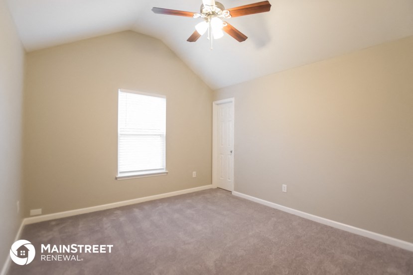 the upstairs bedroom with carpet and a ceiling fan