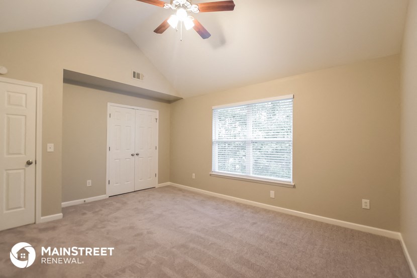 the master bedroom with carpeted flooring and a ceiling fan