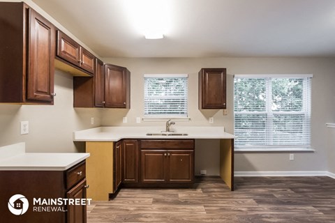 a kitchen with dark wood cabinets and white counter tops and a window