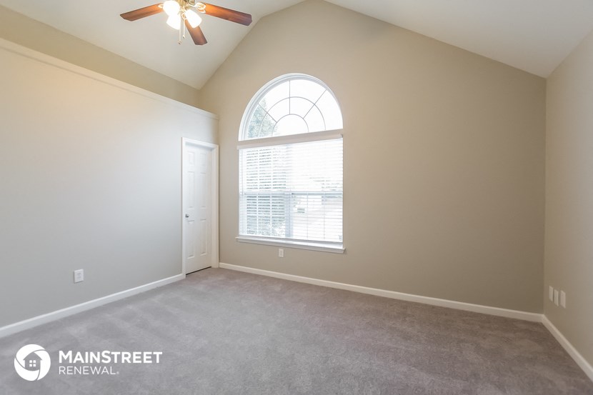the spacious living room with a large window and carpeted flooring