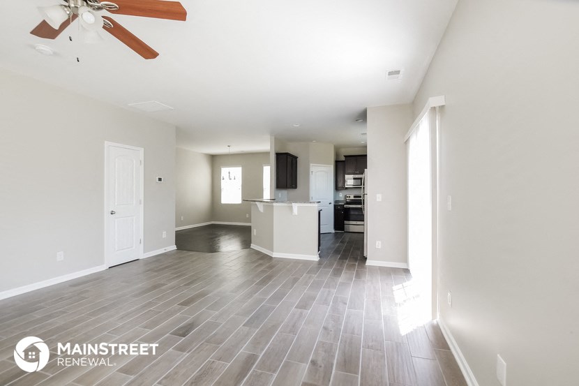 an open living room and kitchen with wood flooring and a ceiling fan