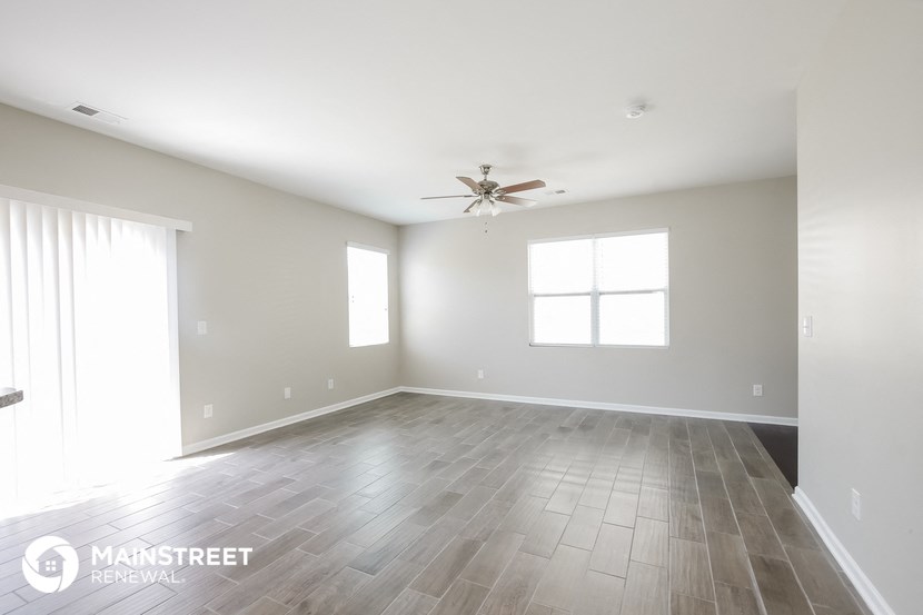 an empty living room with wood floors and a ceiling fan