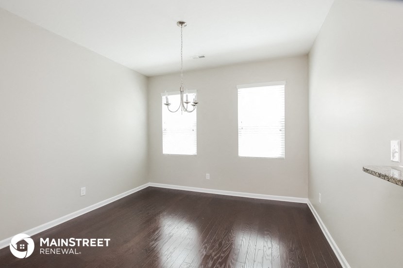 the spacious living room with wood floors and white walls