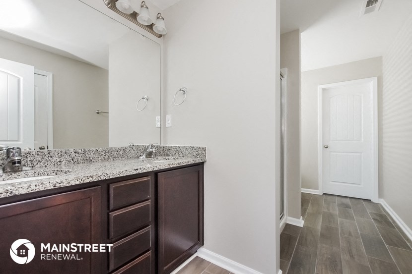 the master bathroom has a large mirror and granite counter tops