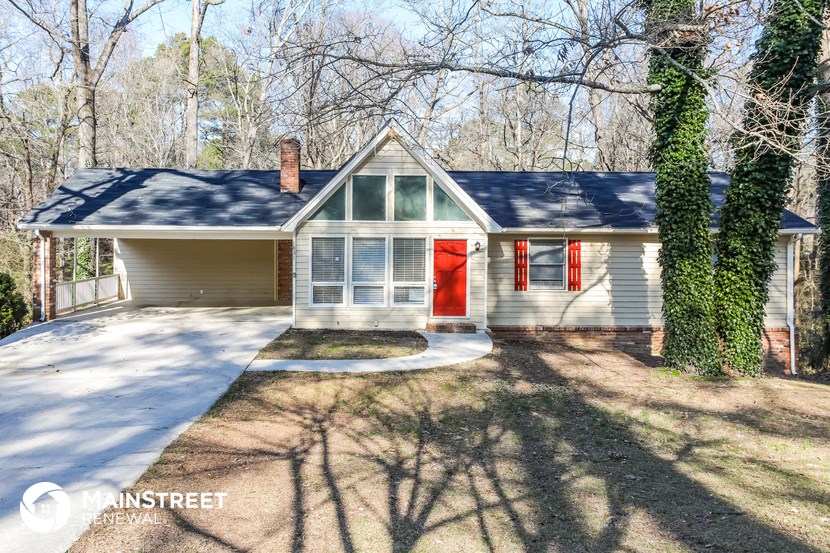 a small white house with a red door on a street