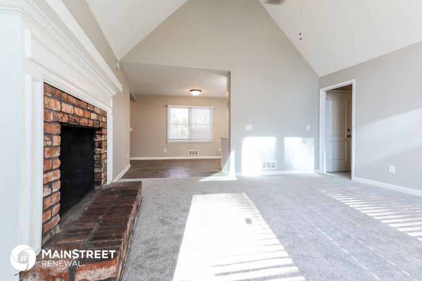 an empty living room with a fireplace and a door to a hallway