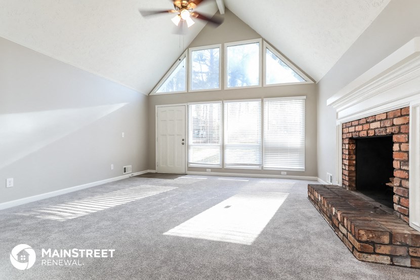 an empty living room with a brick fireplace and a ceiling fan