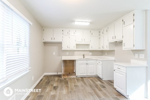 a large white kitchen with white cabinets and wood flooring