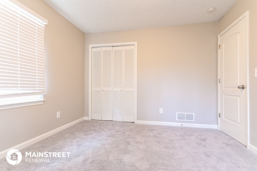 a bedroom with a carpeted floor and a door to a closet