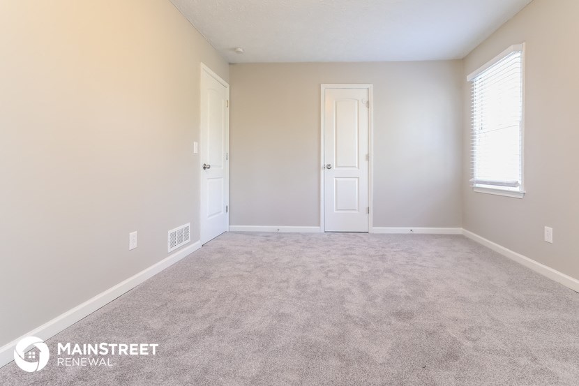 a room with a carpeted floor and a white door and window