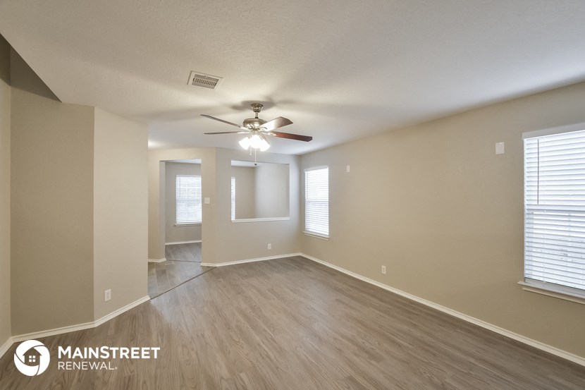 the living room of an empty home with a ceiling fan