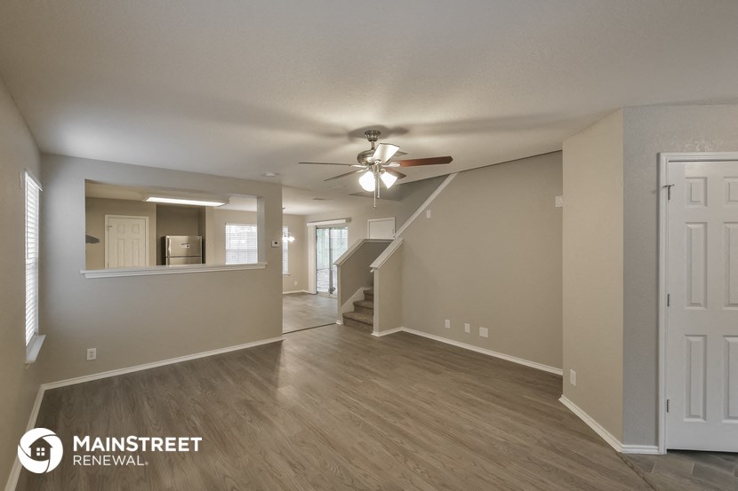the living room and dining room of an empty home with a ceiling fan