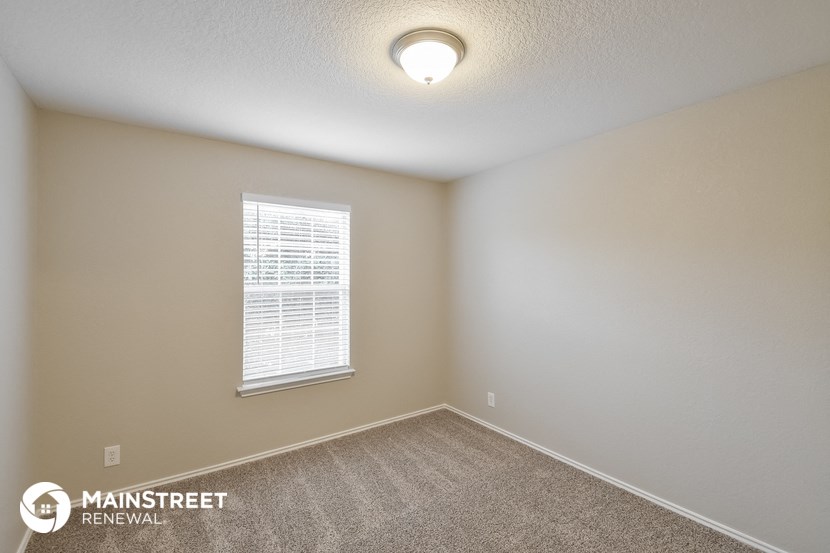 the bedroom of a home with carpet and a window