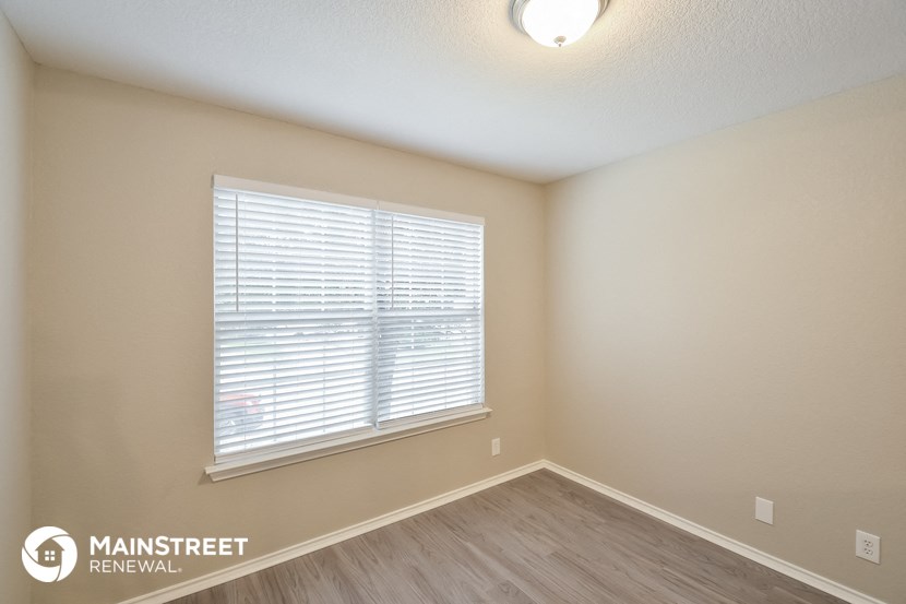 the living room of an apartment with a large window and wooden floors