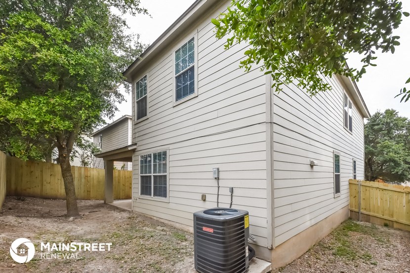 the side of a white house with a water tank in the yard
