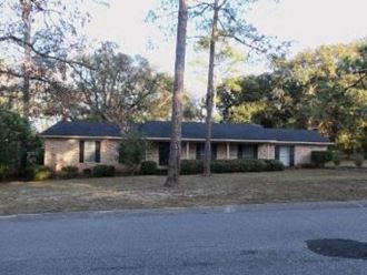 a house on the side of the street with trees