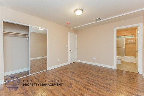 A spacious room with wooden floors and a sliding door.