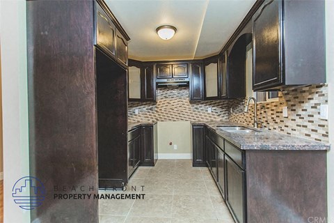 A kitchen with black cabinets and a marble countertop.