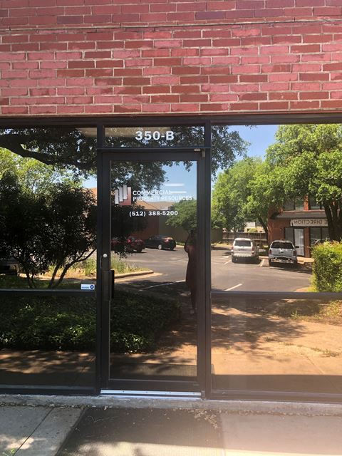 a reflection of the street in a glass door of a brick building