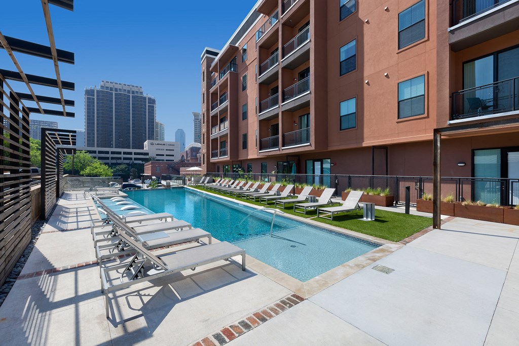 a pool with lounge chairs and a building in the background