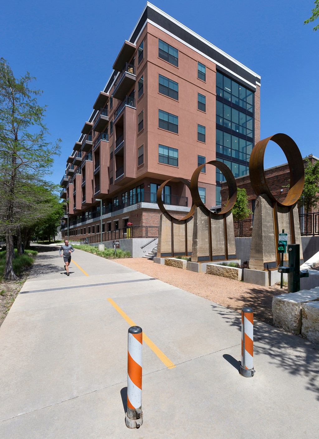 a person walking down a sidewalk in front of a building with an art sculpture on