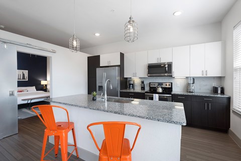 a kitchen with an island with orange chairs and a counter top
