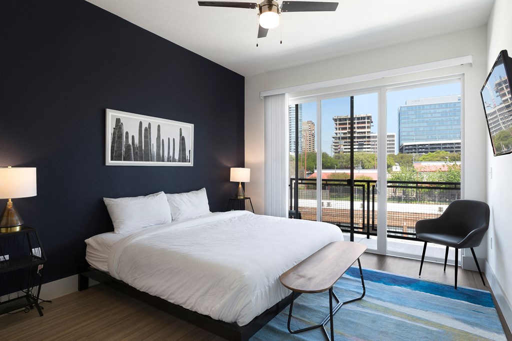 a bedroom with a white bed and a black wall and a balcony