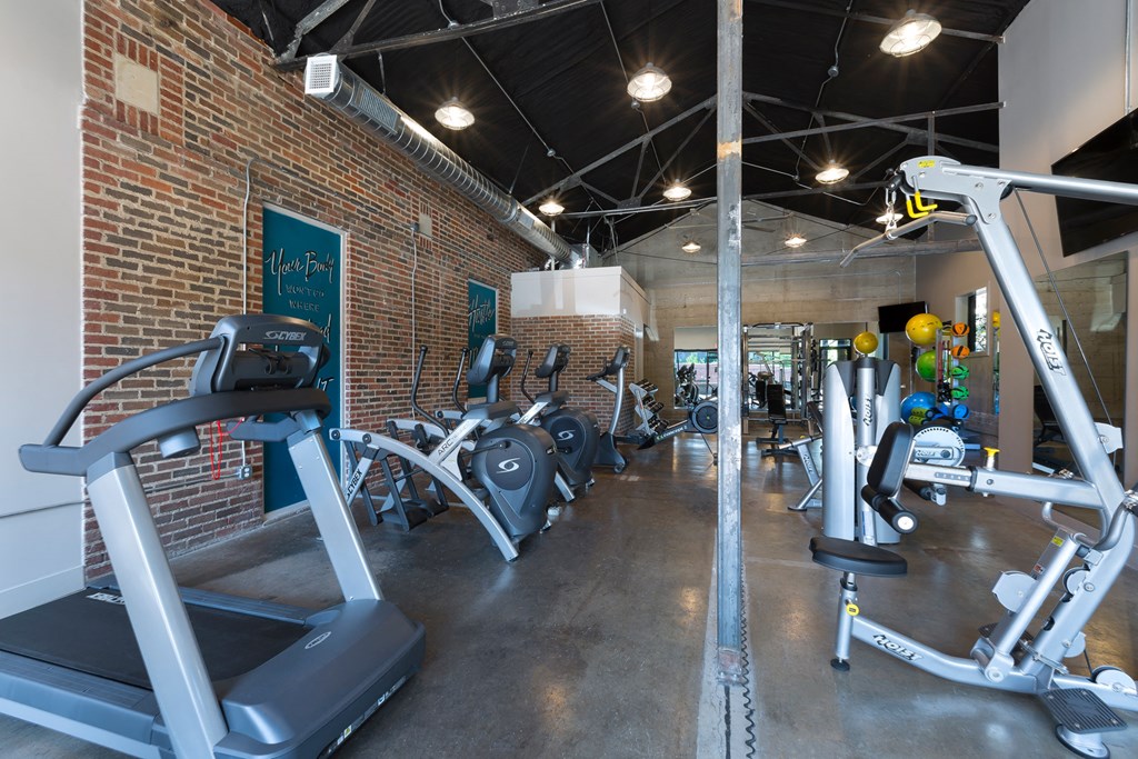a gym with treadmills and weights in a brick wall
