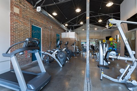a gym with treadmills and weights in a brick wall