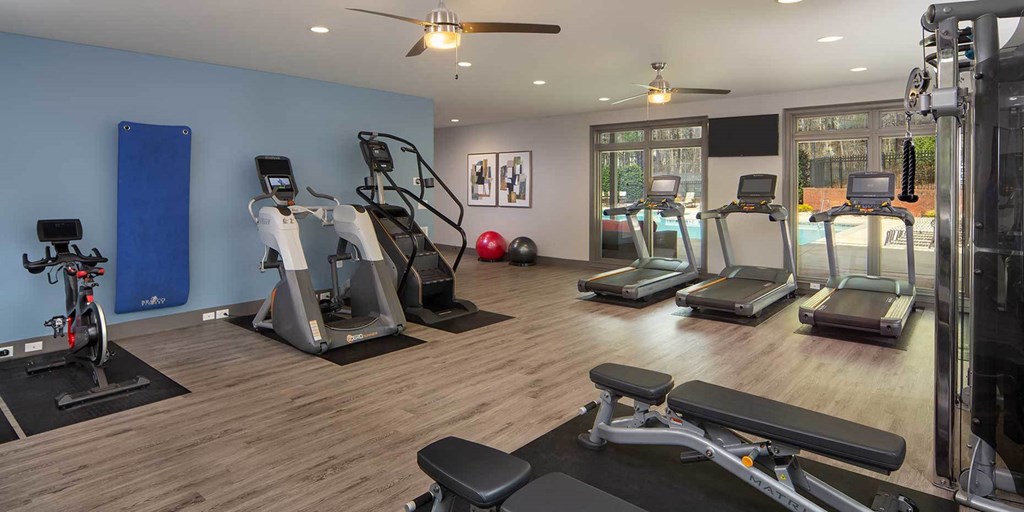 a gym with cardio machines and weights on a wood floor